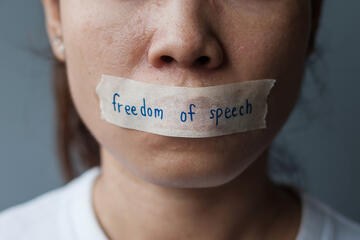 Woman with mouth sealed in adhesive tape with freedom of speech message