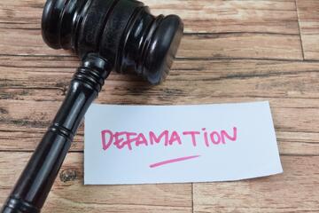 Word "defamation" written on a note © Shutterstock